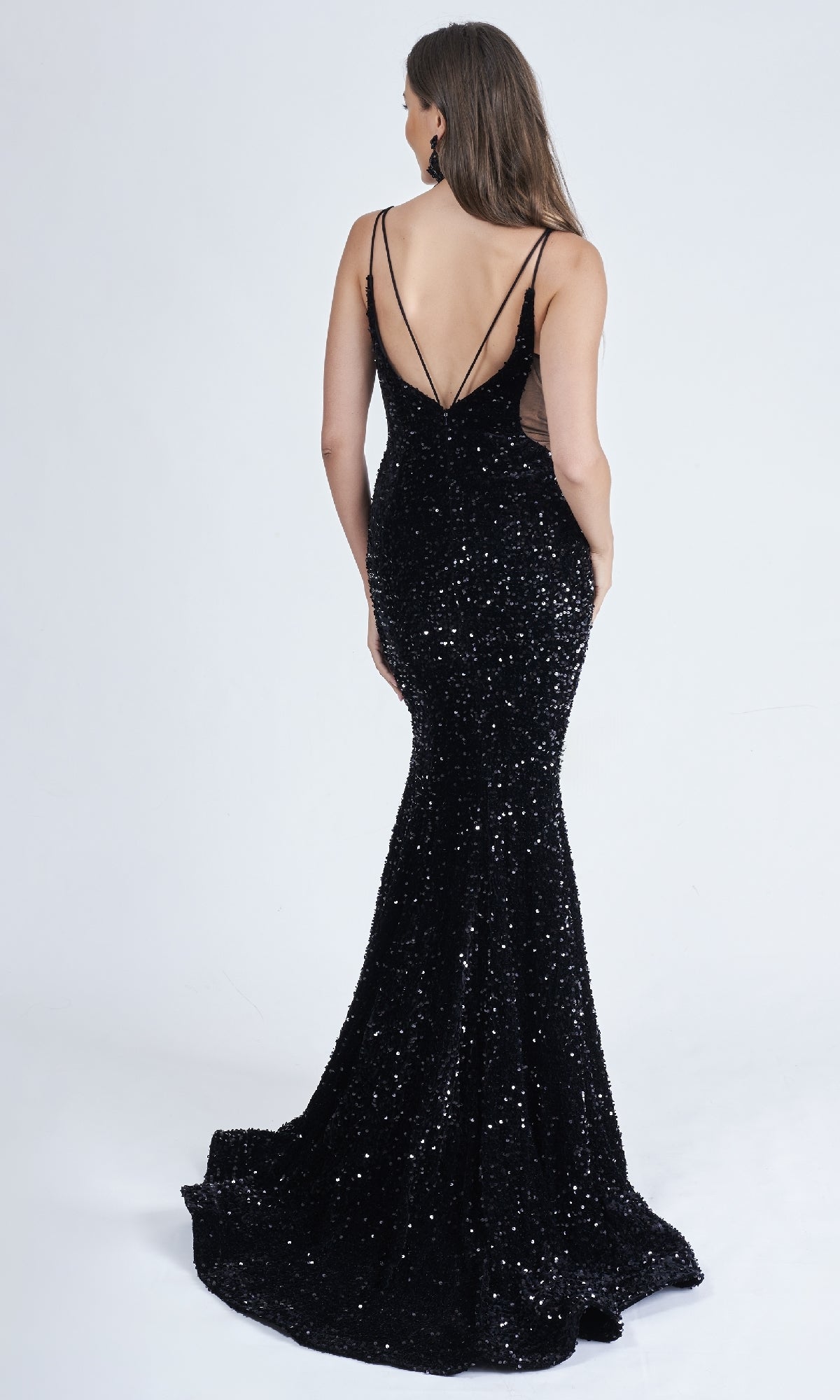 A woman models the Long Formal Sequin Dress: Nina Canacci 4420—black, floor-length with a sheer v-neckline, low-cut back, and thin shoulder straps—standing against a plain white background.